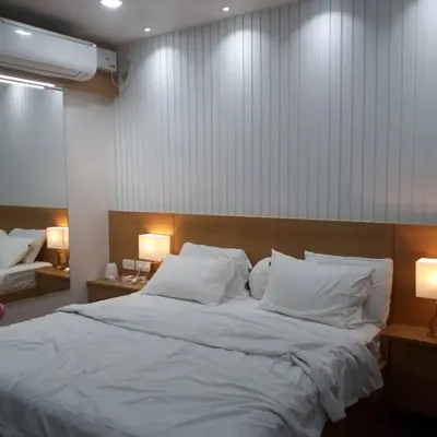 Creating a serene sanctuary for guests is our primary goal in hotel design. The vertical white paneling on the feature wall adds texture and height, while the warm bedside lamps provide a soft, welcoming glow.