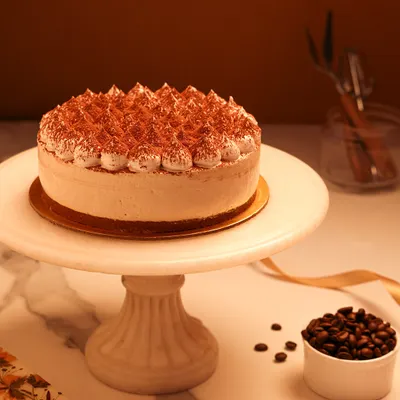 We present a taste of Italy with our classic Tiramisu cake. Featuring layers of coffee-soaked ladyfingers and creamy mascarpone, this cake is finished with piped cream and a generous dusting of cocoa powder for an authentic and elegant dessert experience.