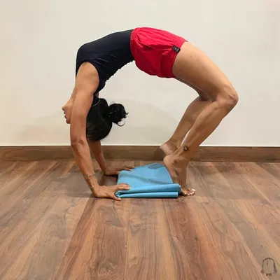 Urdhva Dhanurasana, or Wheel Pose, is a deep backbend that opens the entire front body. Here, the pose is performed with heels lifted on a folded mat to increase the arch in the upper back and open the shoulders.
