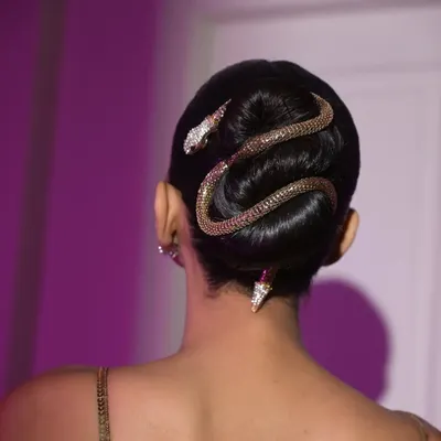 A close-up of the snake accessory coiled around the sleek bun. This shot highlights the precise placement and the high-impact detail that defines this editorial hairstyle.