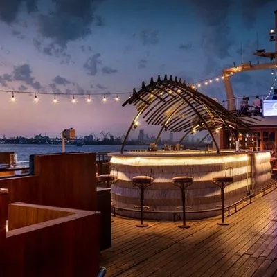 The upper deck of the Queensline Sea Yah at twilight, showing the relationship between the bar, lounge seating, and the open deck. The layout was planned to provide patrons with uninterrupted views of the water and the city, making the location the main attraction.