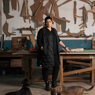 In my workshop, surrounded by my loyal companions. This is my sanctuary, where I am not just a designer, but a hands-on creator. The templates on the wall are the ghosts of past projects, each one a story of a design brought to life.