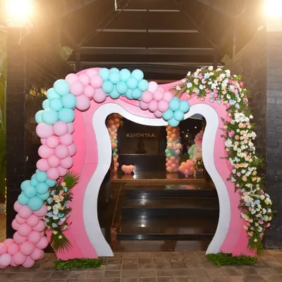 This custom-designed entrance arch for a butterfly-themed party is truly one of a kind. The unique shape is decorated with pink and mint balloons and fresh flowers for a grand and memorable welcome.