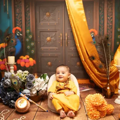 A grand and colorful setup for a baby's Janmashtami photoshoot. This Krishna-themed set features traditional elements like peacock feathers, pots, and rich fabrics.