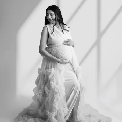 A beautiful black and white portrait of a mom-to-be in a ruffled gown. The window light effect adds depth and artistry to this timeless image.