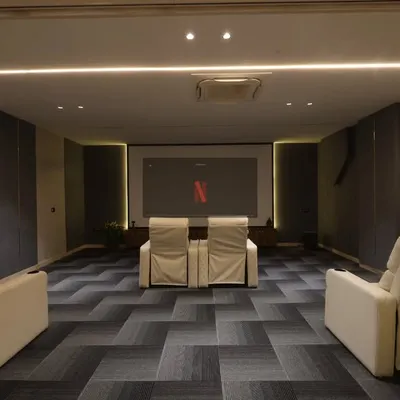 This home theater is designed for an immersive movie experience, with a large screen, acoustic wall panels, and comfortable recliner chairs.