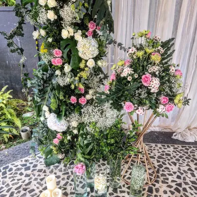 A detailed look at one of our intricate floral installations. This piece combines pink roses, white hydrangeas, and baby's breath with various green leaves like monstera, all set against a mosaic tile floor for a rich, textured look.