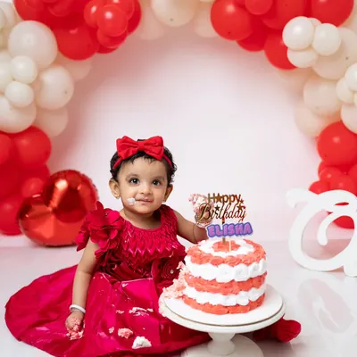A perfect first birthday portrait with a red and white theme. She's just getting a little taste of the cake before the real smashing begins.