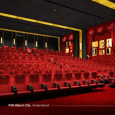 The luxurious PVR auditorium in Hitech City, Hyderabad, featuring plush red velvet seating and classical design elements. The design evokes the glamour of old-world cinema, with tufted wall panels and framed Oscar photographs creating an opulent atmosphere.