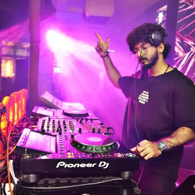 In deep concentration at the console, surrounded by atmospheric stage lighting. My focus is always on the music and the flow of the set.