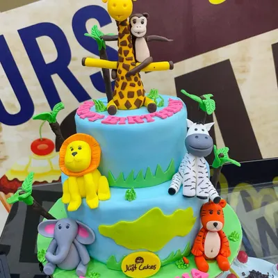 An exciting 3.5kg two-tiered jungle theme cake featuring a whole crew of hand-sculpted fondant animals, including a giraffe, lion, zebra, and monkey.
