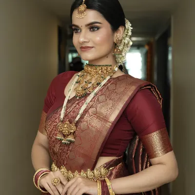 A side profile showcasing the complete South Indian bridal look, from the traditional maang tikka and gajra in her hair to the layered temple necklaces. The makeup remains flawless and radiant from every angle.