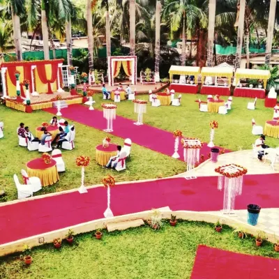 An aerial view of a large outdoor wedding setup on a lawn, showing the stage, guest seating, and red carpet walkways all arranged by my team.