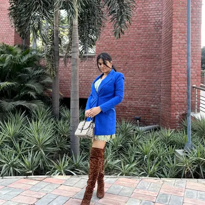 A full-length view of this bold street style look. I paired a royal blue blazer with a short, light green printed dress and finished it with daring leopard-print thigh-high boots and a designer bag. This is how you make a statement on a regular day.