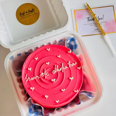 A fun and quirky bento cake with a bright pink swirl design and the message "pyaar ek dhoka hai". It's perfect for a laugh with a friend.