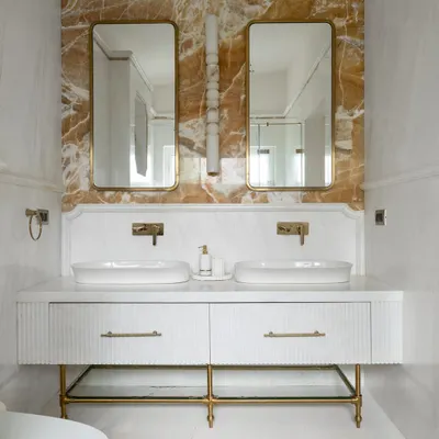 The master en-suite at Verdant Manor, anchored by a dramatic Mango Onyx accent wall and a floating white vanity. We used fluted detailing on the drawers and a checkerboard floor tile pattern to add layers of texture and geometry.
