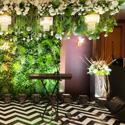 A perfect setup for a live band or DJ at a Sangeet. We created a lush green foliage wall as a backdrop, with a ceiling installation of hanging greenery, chandeliers, and disco balls over a bold chevron dance floor.