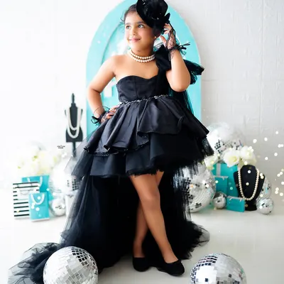 Channeling her inner Audrey Hepburn! This little fashionista is striking a pose in a "Breakfast at Tiffany's" inspired photoshoot. The custom black dress and pearl necklace complete the glamorous look.