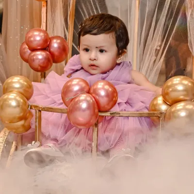 A candid portrait of the birthday girl, Yasmeen, during her first birthday celebration. I aimed to capture her innocent curiosity amidst the beautiful party decor of pink and gold balloons.