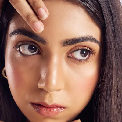 The essence of a skin-focused look. This close-up shows a "barely there" application, focusing on a dewy, radiant complexion, groomed brows, and a glossy lip. It's all about letting the skin breathe.
