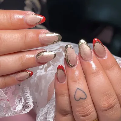 A bold and beautiful set featuring a sheer nude base with a striking red and gold chrome double French tip.
