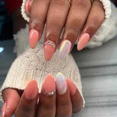 A beautiful peach-colored manicure with glamorous accents. This set features an iridescent chrome accent nail and delicate silver chain details for a touch of bling.