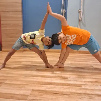Two boys from our summer camp create a partner triangle pose. Our kids' yoga sessions focus on making fitness collaborative and enjoyable.