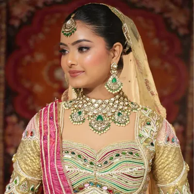 A close-up of the magnificent emerald and kundan bridal jewellery set. This royal necklace, paired with a matching maang tikka and earrings, is available to rent for your big day.