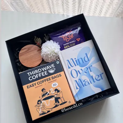 A wellness hamper perfect for International Yoga Day. It includes a "Mind Over Matter" journal, Third Wave coffee bags, and healthy snacks to encourage a moment of pause and reflection.