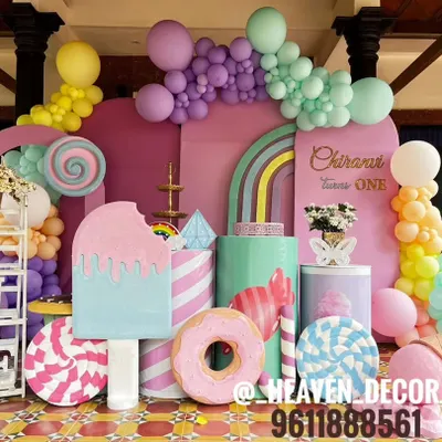 A spectacular Candyland-themed first birthday party, filled with oversized props. The setup includes giant ice cream, donut, and lollipop cutouts, all in a vibrant pastel color palette.