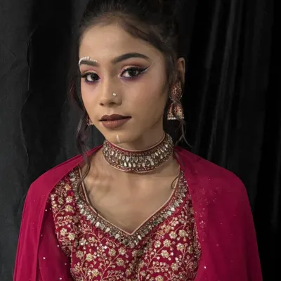 A creative airbrush makeup look featuring decorative pearl bindis and sharp, graphic eyeliner. This demonstrates how airbrush techniques can be used for both a flawless base and artistic details.