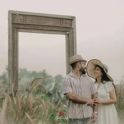 Framing their love story. A creative shot using a large empty frame as a prop in a field of tall grass.
