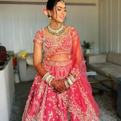 A beautiful bridal updo for a day wedding. I created a neat bun and adorned it with fresh pink flowers to match her lehenga.