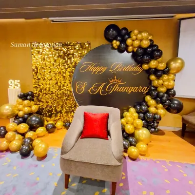 A grand 95th birthday celebration with a classic black and gold theme. The setup includes a gold sequin wall, a personalized circular backdrop, and a balloon arrangement.