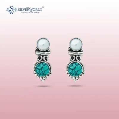 These elegant earrings feature a vibrant turquoise stone set in an oxidized silver frame, topped with a luminous white pearl. The design combines color and classic elements for a sophisticated look.