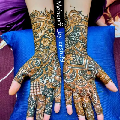 A stunning example of a full-coverage bridal design with fresh, dark henna paste. The contrast highlights the intricate details, including checkerboard fills, delicate vines on the fingers, and bold floral work on the palms.