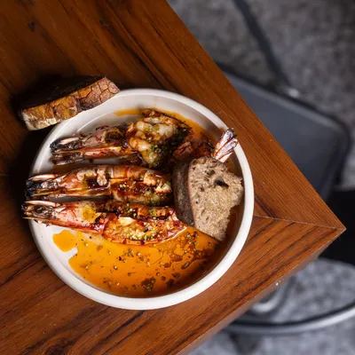 When the flames kiss the prawns and the butter starts to sizzle, there is a kind of magic that fills the air. My King Prawns are slow-cooked with garlic butter and fermented chilli, perfect for scooping up with warm sourdough.