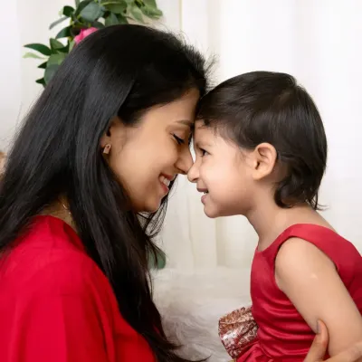 An intimate close-up of a mother and daughter touching foreheads and smiling, a simple and powerful expression of their love.