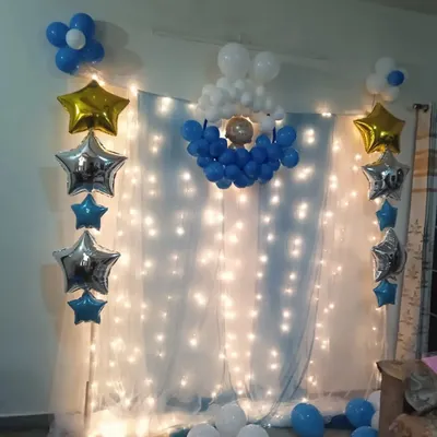 A simple backdrop created with a white curtain and fairy lights. I added star-shaped foil balloons and small blue and white balloon arrangements to create a dreamy, celestial theme.