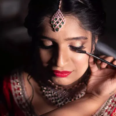 A quiet moment of focus. Applying mascara is one of the final, crucial steps to making the eyes pop. This close-up shows the detail that goes into creating a dramatic and beautiful Sangeet eye makeup look.