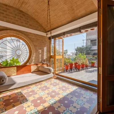 The semi-outdoor family space at Audumbara, featuring our custom-designed teak and rattan swing. The vaulted brick roof and patterned tiles create a captivating retreat.