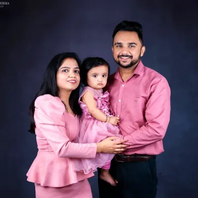 A beautiful family portrait against a dark backdrop. The coordinated pink outfits create a soft and loving feel in this classic standing pose.