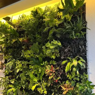 A detailed view of a dense, jungle-style artificial wall. The mix of ferns, broadleaf plants, and trailing vines creates a rich, textured, and hyper-realistic look.