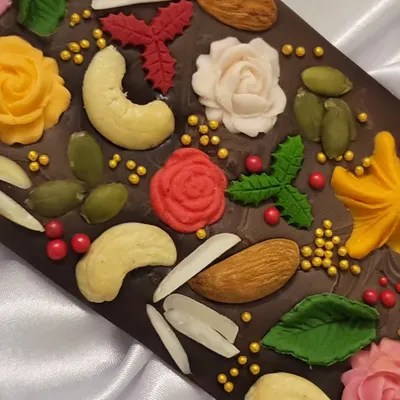 A close-up of my signature dark chocolate bar. I carefully place each nut, seed, and handmade flower so every bar is unique and beautiful. This is a perfect gift for any chocolate lover.
