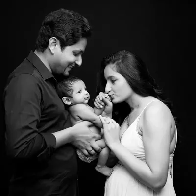 A beautiful family of three. This black and white portrait captures a tender moment between parents and their awake, curious newborn, showcasing the beginning of their new life together.