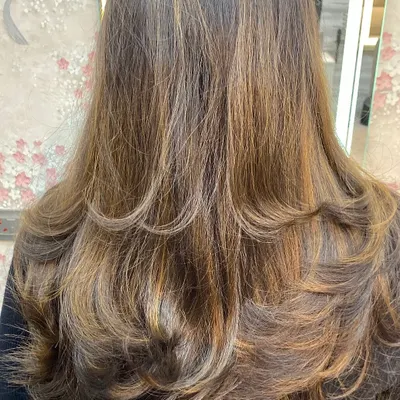 A layered haircut with subtle highlights, styled with an inward curl to create volume and shape.