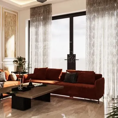 The main seating area of the Lajpat Nagar vacation home, designed to be bright and airy. The rust-colored sofa adds a pop of warmth against the neutral marble flooring and sheer curtains that filter the natural light beautifully.