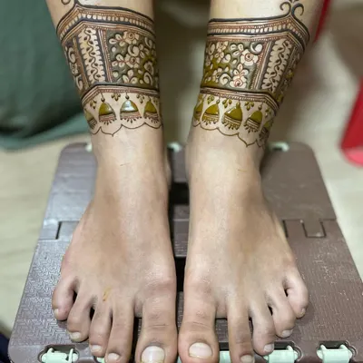 The first step of a bridal leg design. This shows the delicate floral band with hanging 'jhumki' or bell motifs.