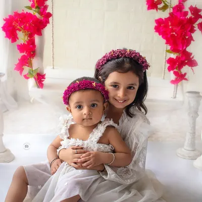The sweetest sibling hug. The matching white dresses and floral crowns, set against a pop of bright pink flowers, make this a picture-perfect moment.