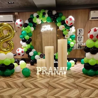 A fun football-themed birthday for an 8-year-old, featuring a green, black, and white balloon ring, football balloons, and personalized name blocks.
